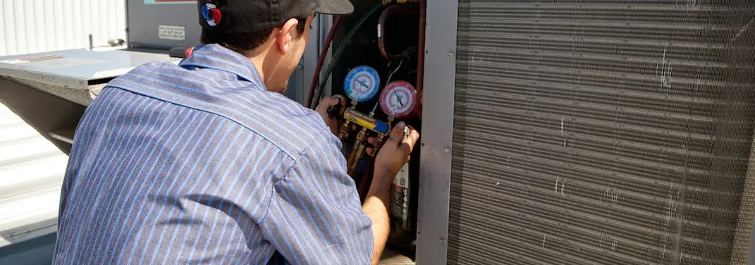 HVAC technician servicing a condenser unit in Slaton